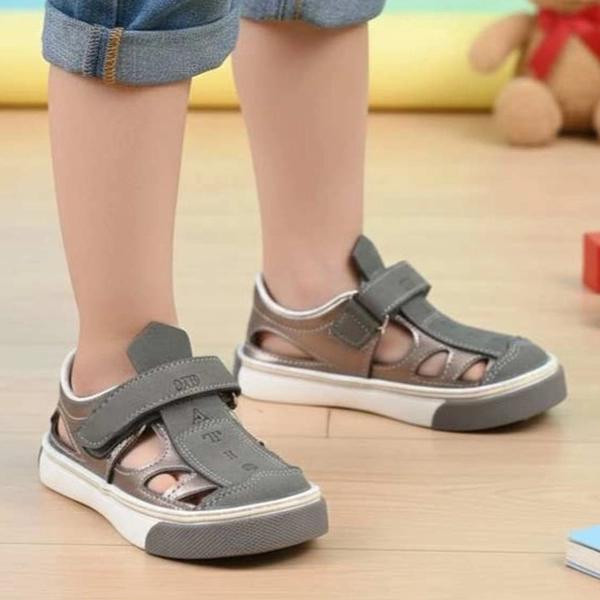 alt: صندل بچگانه داتیس مدل دانیال رنگ طوسی پوشیده شده روی پا، مناسب استفاده روزمره کودک