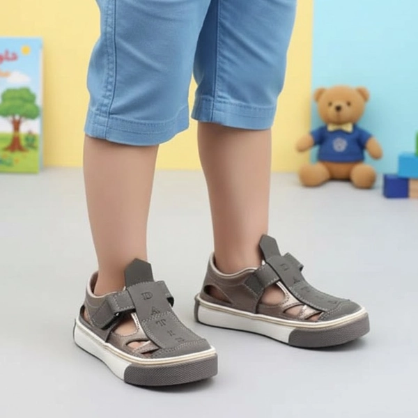 alt: صندل بچگانه داتیس مدل دانیال رنگ طوسی پوشیده شده روی پا، مناسب استفاده روزمره کودک